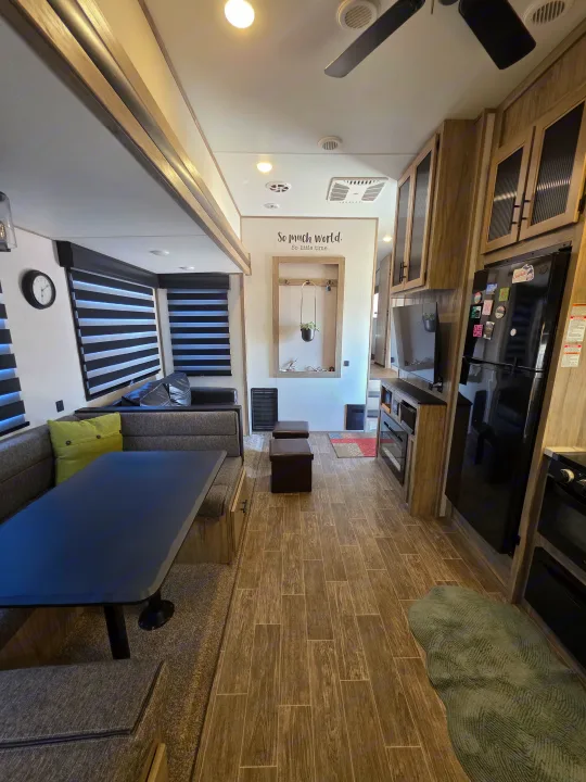 Spacious RV rental interior with dining booth, kitchen, living area, and stylish wood-look flooring.. Forest River Cherokee Arctic Wolf 2021