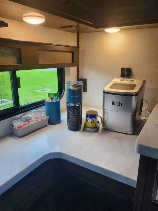 RV rental counter with a Keurig, an ikich ice machine, & hot drink supplies next to a window.. Dutchmen Yukon 2021