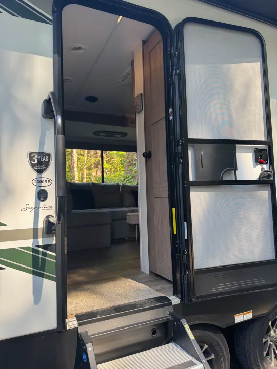 Open door of a Signature Series RV rental, revealing inviting steps and a comfortable interior living area.. Heartland RVs Eddie Bauer 2024
