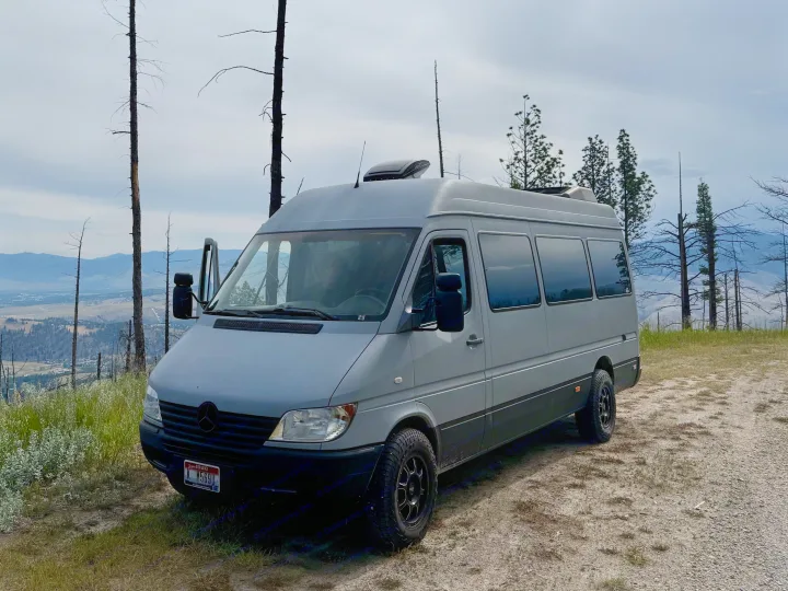Grey camper van parked on a scenic Idaho overlook with mountain views, perfect for an RV rental adventure.. Dodge Sprinter 2006