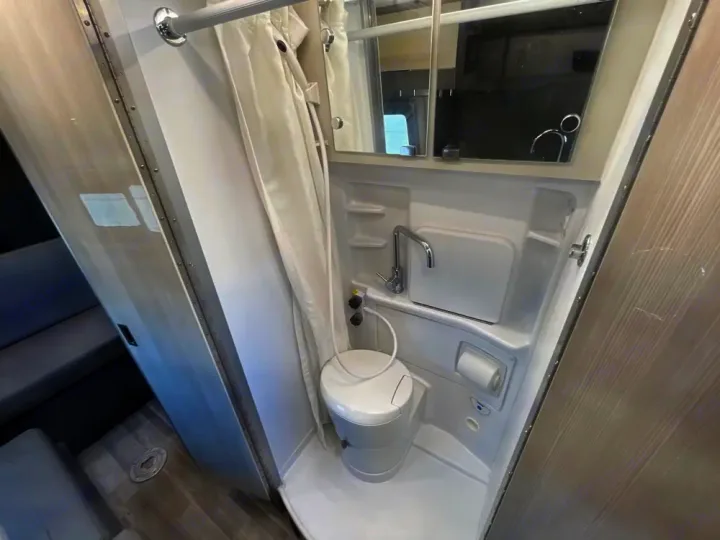 Compact rv rental bathroom: all-in-one shower, toilet, and sink. Bright interior perfect for your travel needs.. Thor Tranquility 2022