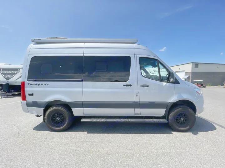 Side view of a silver Mercedes-Benz Sprinter "Tranquility" camper van, available for RV rental, parked on asphalt.. Thor Tranquility 2022