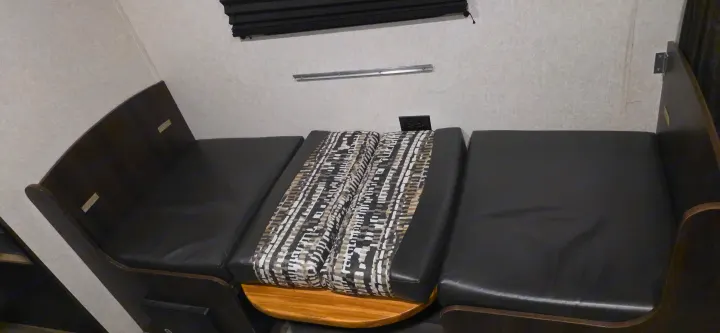 RV rental dinette: dark bench seats with a convertible table and patterned cushions, offering versatile seating & sleeping.. Jayco Jay Flight SLX 2018