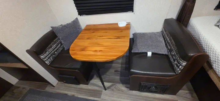 RV rental dinette setup: a warm wooden table flanked by dark booth seats with gray pillows, ideal for a compact space.. Jayco Jay Flight SLX 2018