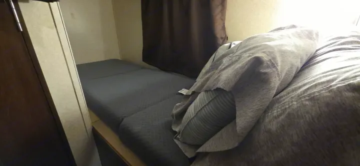 Cozy rv rental interior: A compact sleeping area with a grey modular bed, pillow, and blanket. Functional travel space.. Jayco Jay Flight SLX 2018