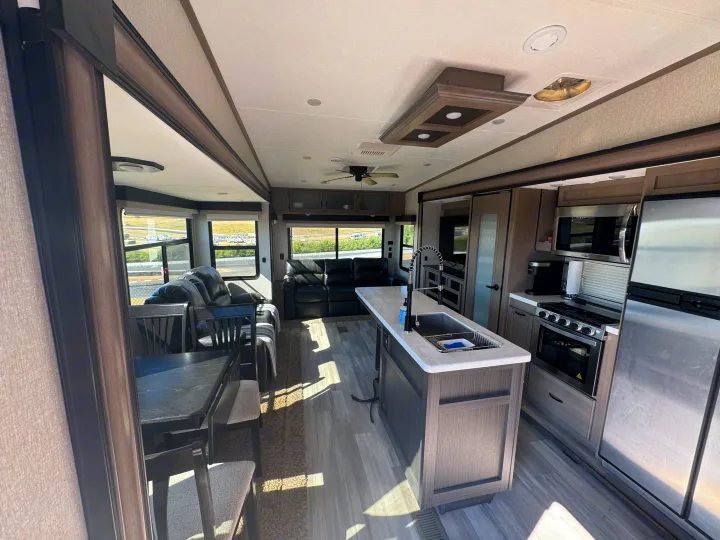Inside our RV rental: a bright kitchen island, full appliances, comfy living room with recliners, and dining area. Modern and ready.. Coachmen Chapparal 336 TSIK 2022