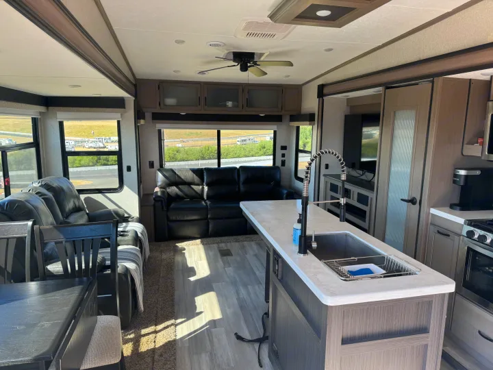 Spacious RV rental interior featuring a modern kitchen island, comfortable living area with recliners, and large windows.. Coachmen Chapparal 336 TSIK 2022