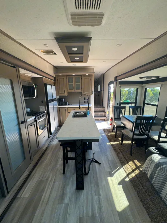 Spacious modern RV rental interior featuring a full kitchen, island, and dining area. Perfect for comfortable travel.. Coachmen Chapparal 336 TSIK 2022