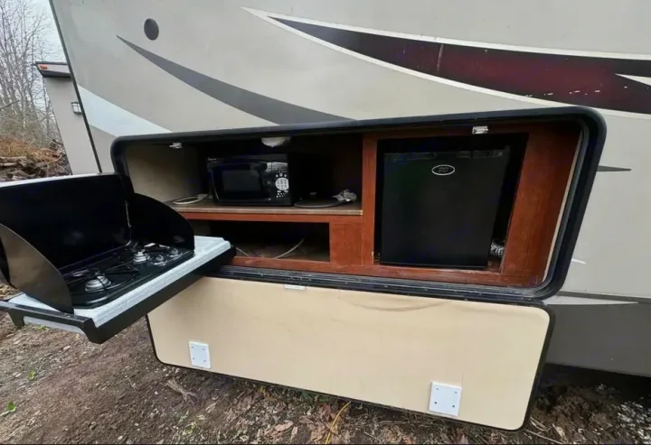 RV rental outdoor kitchen setup. Features a pull-out two-burner stove, microwave, and mini-fridge for convenient camping meals.. Evergreen RV Sun Valley 2014