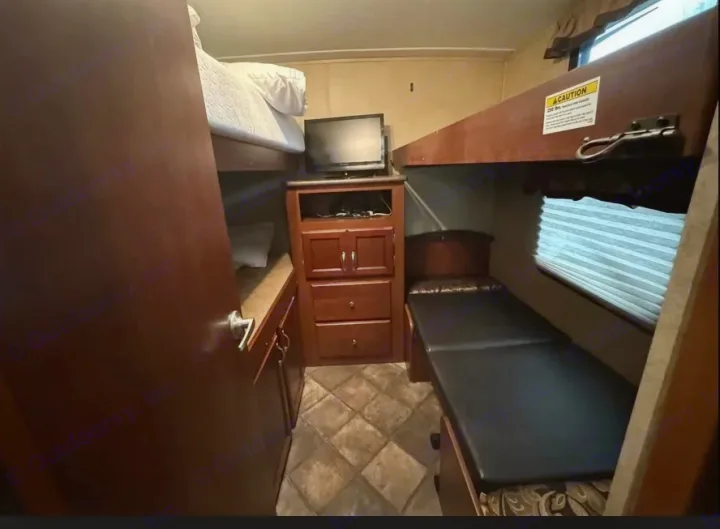 Compact RV rental bunk room showing three beds, a TV, and storage for a comfortable family trip.. Evergreen RV Sun Valley 2014