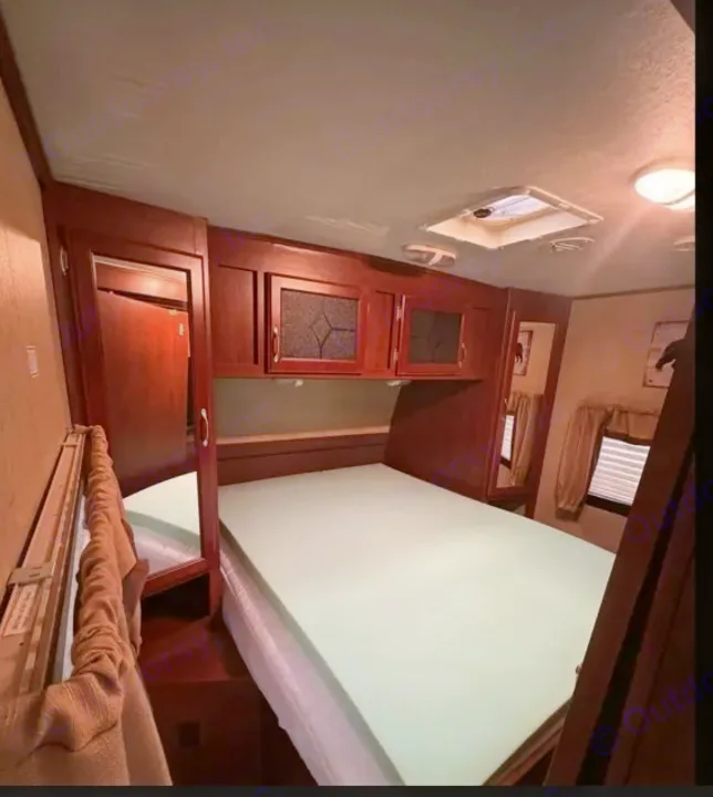 RV rental bedroom interior with a bed, light green foam topper, wood cabinets, and a ceiling skylight.. Evergreen RV Sun Valley 2014