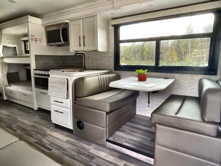Spacious RV rental interior featuring a full kitchen, dinette area, and bunk beds with clean, modern design.. Entegra Odyssey 2025