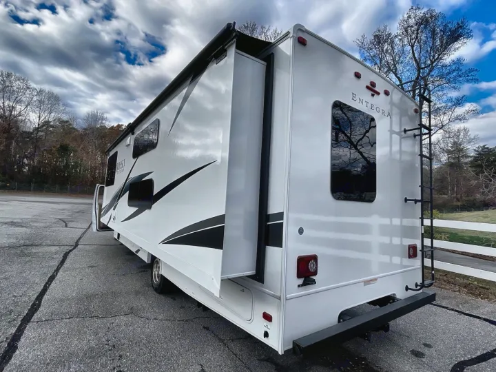 Spacious white RV rental, an Entegra Odyssey motorhome with extended slide-out, parked on asphalt. Ideal for road trips.. Entegra Odyssey 2025