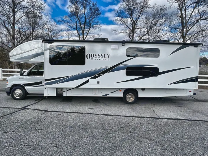 This white "Odyssey Entegra" RV rental is parked outdoors. This motorhome is ready for your next adventure.. Entegra Odyssey 2025