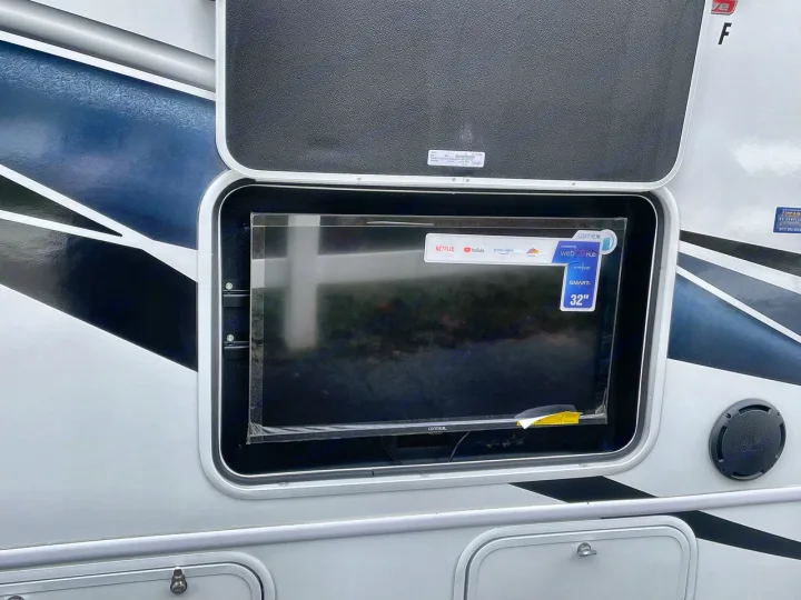 New 32" smart TV setup for outdoor entertainment in this RV rental, complete with an adjacent speaker.. Entegra Odyssey 2025