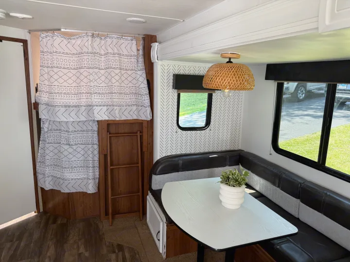 Cozy RV rental interior featuring a bright dinette area, patterned walls, and bunk beds with unique curtains, ideal for travel.. Gulf Stream Conquest 2016