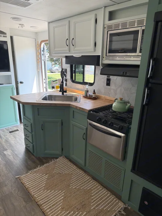 Modern renovated RV kitchen with sage green cabinets, wood counters, and hexagon backsplash. Perfect for your next rv rental adventure.. Gulf Stream Conquest 2016