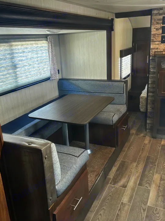 Inside your RV rental: a modern dinette with booth seating, under-bench storage, and large windows, ready for meals and relaxation.. Forest River Cherokee Grey Wolf 2020