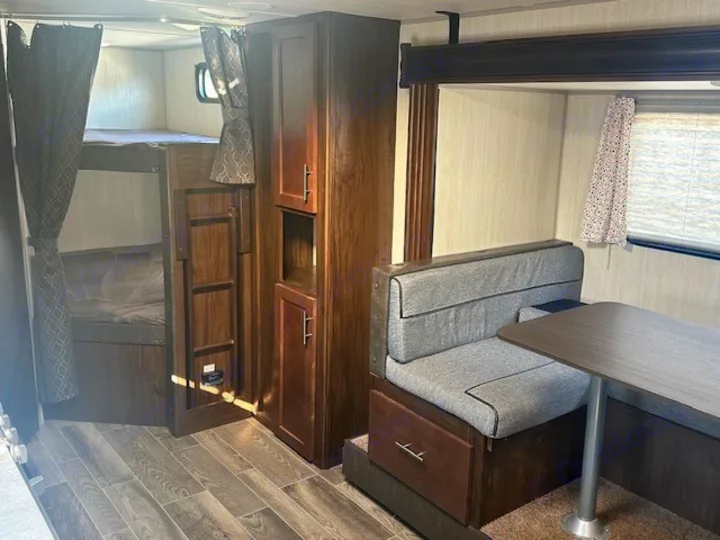 Cozy rv rental interior featuring bunk beds with privacy curtains, a storage cabinet, and a dinette for eating/lounging.. Forest River Cherokee Grey Wolf 2020