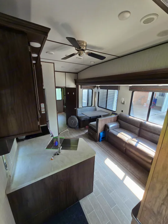 Modern RV rental interior showing a kitchen, dining booth, and sofa under bright windows.. Forest River Cherokee Arctic Wolf 2019