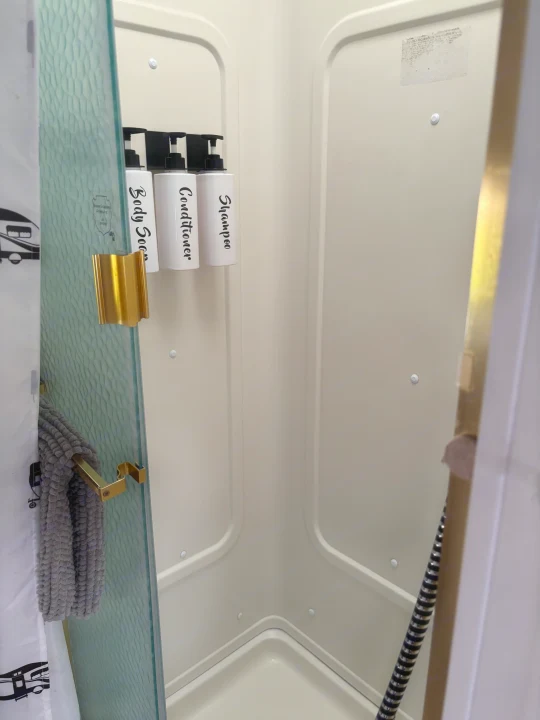 Clean RV rental shower featuring convenient wall-mounted soap, conditioner, and shampoo dispensers, ready for your travels.. Jayco Greyhawk 2005