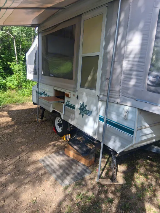 Pop-up RV rental set up in a serene outdoor camping spot, offering a comfortable travel adventure.. Bonair 1050C 1996