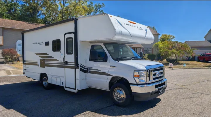 Bright white Coachmen Freelander Class C motorhome RV rental parked on a sunny suburban street, ready for adventure.. Forest River Coachmen Freelander 2021