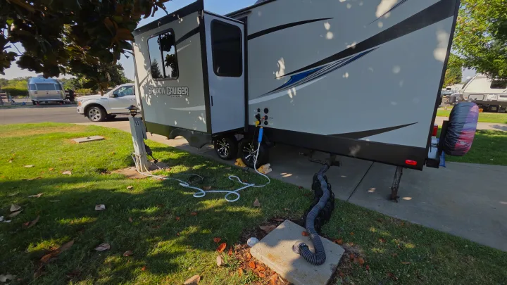 A Shadow Cruiser RV rental is parked at a shaded campground site, fully hooked up to water, power, and sewer.. Shadow Cruiser 240RBH 2019
