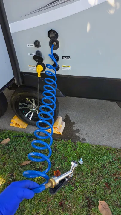 RV rental setup: Camper connections for water, electric, cable, and satellite, with a blue coiled sprayer hose.. Shadow Cruiser 240RBH 2019