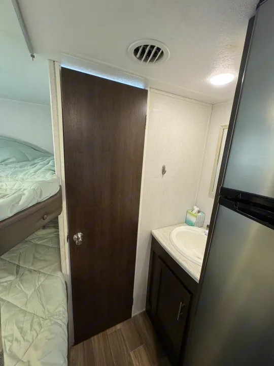 RV rental interior: bunk beds, a compact bathroom with sink, and a refrigerator. Efficiently designed for travel.. Forest River Wildwood X-Lite 2019
