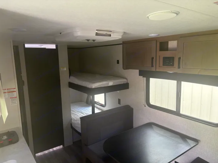 RV rental interior with double bunk beds, dinette seating, and overhead storage. This camper offers a cozy living space.. Jayco Jay Flight SLX 2025