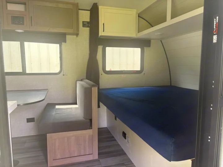 RV rental interior showcasing a compact living space with a dinette, bed, and overhead storage.. Jayco Jay Flight SLX 2025