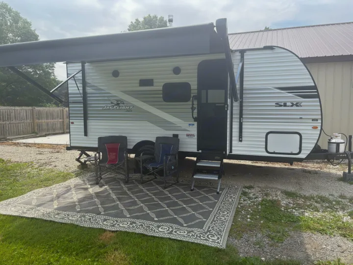 Jay Flight RV rental features an extended awning, outdoor rug, camping chairs, and steps.. Jayco Jay Flight SLX 2025