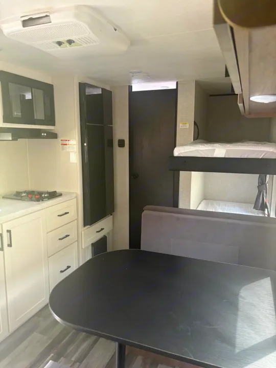 This RV rental interior showcases a full kitchen, dining area with a table, and bunk beds for sleeping.. Jayco Jay Flight SLX 2025