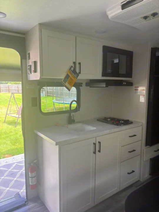 This RV rental features a well-equipped kitchen with sink, stovetop, microwave, and a window view to nature.. Jayco Jay Flight SLX 2025