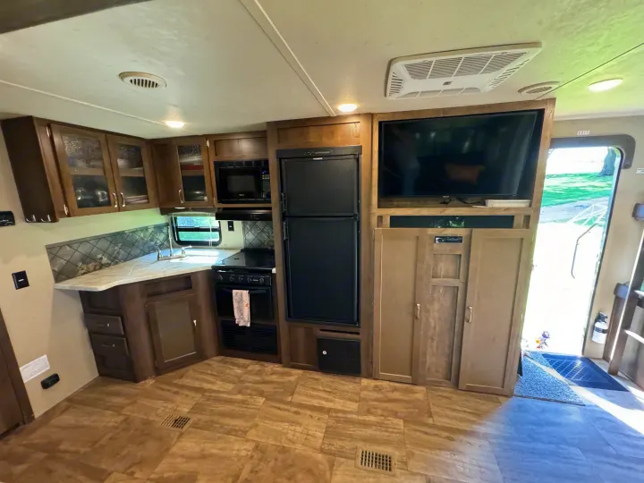 Spacious RV rental interior featuring a modern kitchen, living area with TV, and ample cabinetry for a comfortable stay.. Forest River Palomino Puma 2018