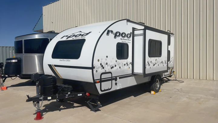 A white and grey r-pod by Forest River travel trailer, perfect for an RV rental, sits ready next to another camper.. Forest River R-Pod 2021