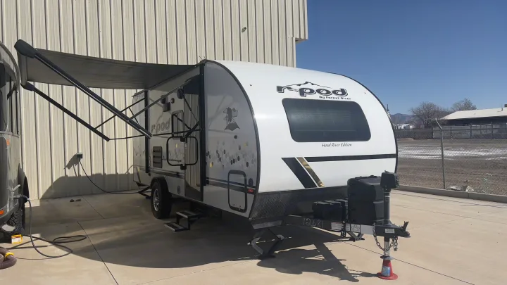 White r-pod travel trailer RV rental with extended awning, parked on concrete, power connected.. Forest River R-Pod 2021