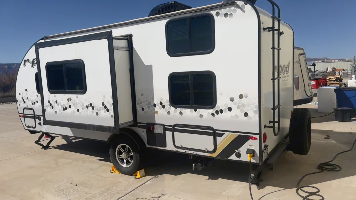 Modern white r-pod RV rental with a distinctive hexagonal pattern, tinted windows, and rear ladder, parked on concrete.. Forest River R-Pod 2021