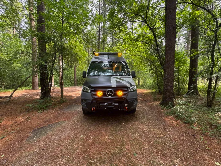 A custom Sprinter camper van, great for an RV rental, parked on a forest path with bright lights.. Mercedes-Benz Sprinter RV Motorhome Campervan 2022