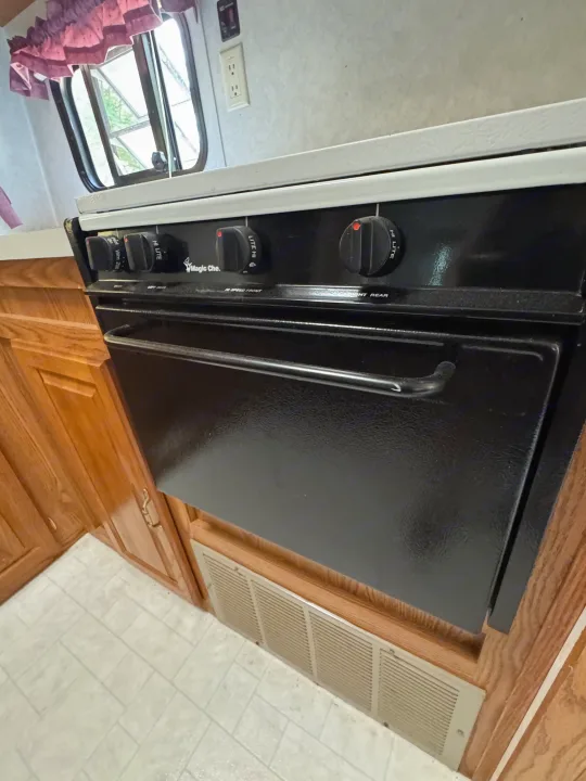 Enjoy home-cooked meals in this RV rental kitchen, featuring a black Magic Chef stove and oven for your travel convenience.. Forest River Wildwood 2000