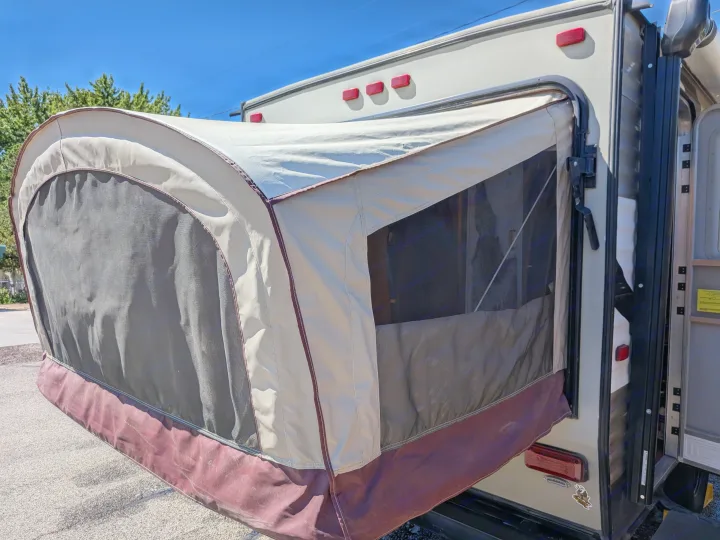 Rear view of an RV rental with its pop-out tent extension deployed, showcasing the canvas and mesh features for camping comfort.. Starcraft AR-One 2015