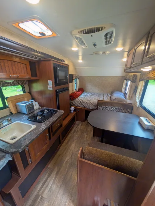 Step inside this RV rental! Features a compact kitchen, dining booth, and comfortable bed area, perfect for travel.. Jayco Hummingbird 2017