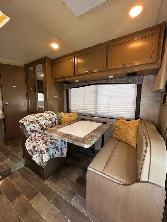 RV rental interior features a comfortable dinette with a patterned blanket, storage, and window blinds.. Thor Chateau 2022