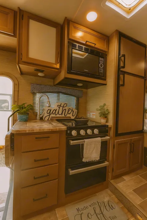 Spacious RV rental kitchen with modern appliances like an oven, microwave, and refrigerator, offering comfort for travelers.. Thor Chateau 2022
