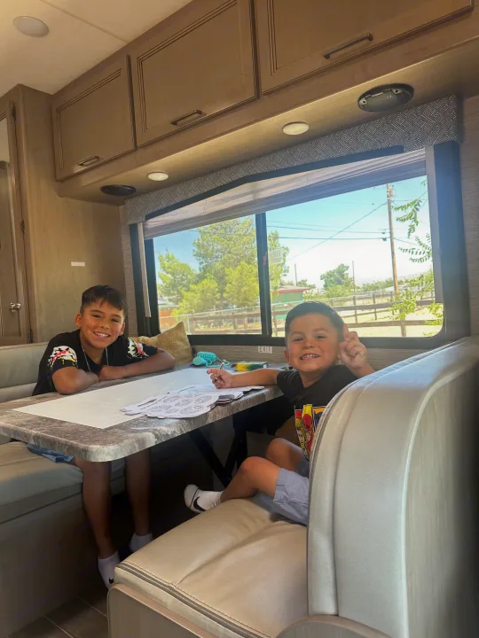 Kids enjoy coloring at the dinette in an RV rental. A fun activity during their family adventure.. Thor Chateau 2022