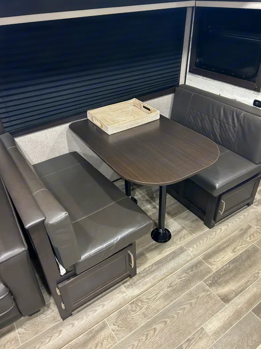 Cozy RV rental dinette featuring dark upholstered benches, a sturdy table, and integrated storage below.. Jayco Jay Feather 2021