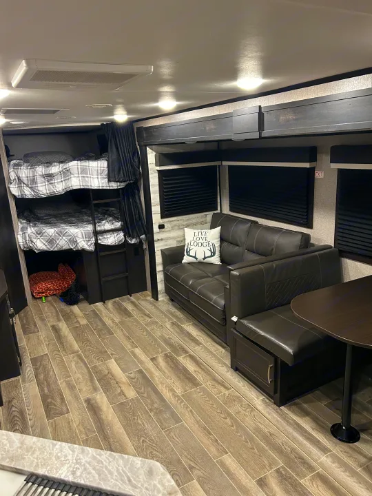 Modern RV rental interior featuring bunk beds, a comfortable sofa, and a dinette for a cozy travel experience.. Jayco Jay Feather 2021
