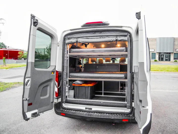 Rear interior of an RV rental camper van, featuring a versatile modular bunk bed and integrated storage system.. Ford Transit 2019