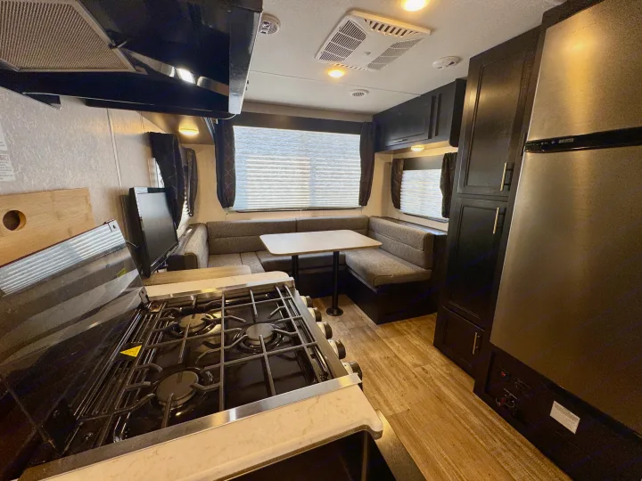 Clean RV rental interior featuring a kitchen with stove, counter space, a U-shaped dinette, and large refrigerator.. Forest River Grey Wolf Limited 2022